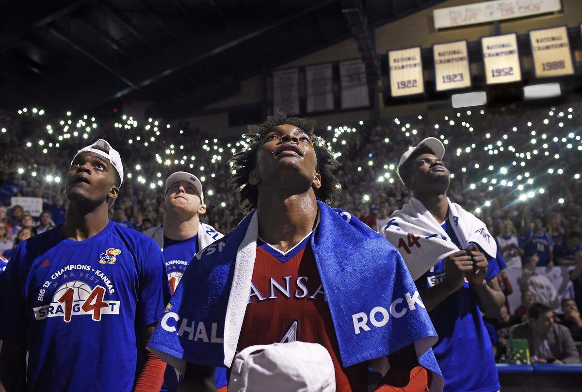 For one last night, KU senior Devonte’ Graham got to bask in the glow of light at Allen Fieldhouse. After the Jayhawks beat Texas 80-70 on Senior Night, it was time to celebrate winning a 14th consecutive Big 12 Conference title. Graham was joined by teammates Lagerald Vick (left) and Udoka Azuibuike as a video highlight reel of the season played above them.