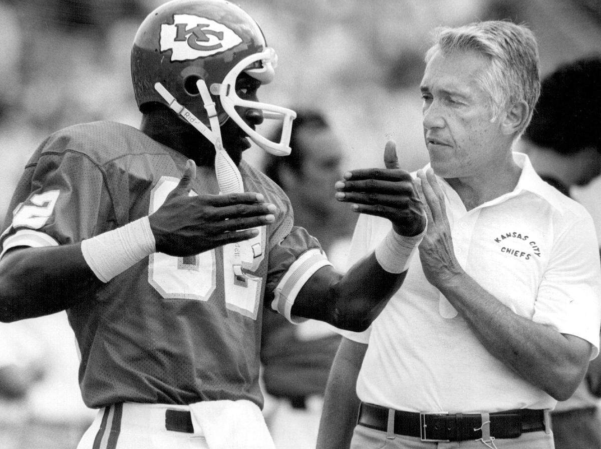 Jerrold McRae, Chiefs’ wide receiver, and Marv Levy confer on the sidelines after a pass went awry. Levy served as head coach of the Kansas City Chiefs from 1978 to 1982, leading the team through steady improvement during his tenure. Despite his efforts, Levy was dismissed after the strike-shortened 1982 season, finishing with a 31–42 record.