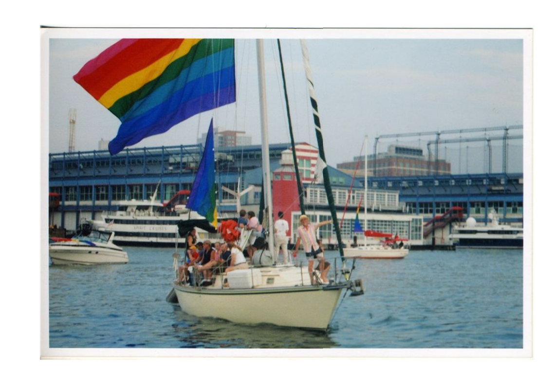 LGBTQ+ artist and native Kansan Gilbert Baker is seen on a sailboat with friends in 2010 flying a version of the eight-stripe rainbow pride flag he designed in 1978.