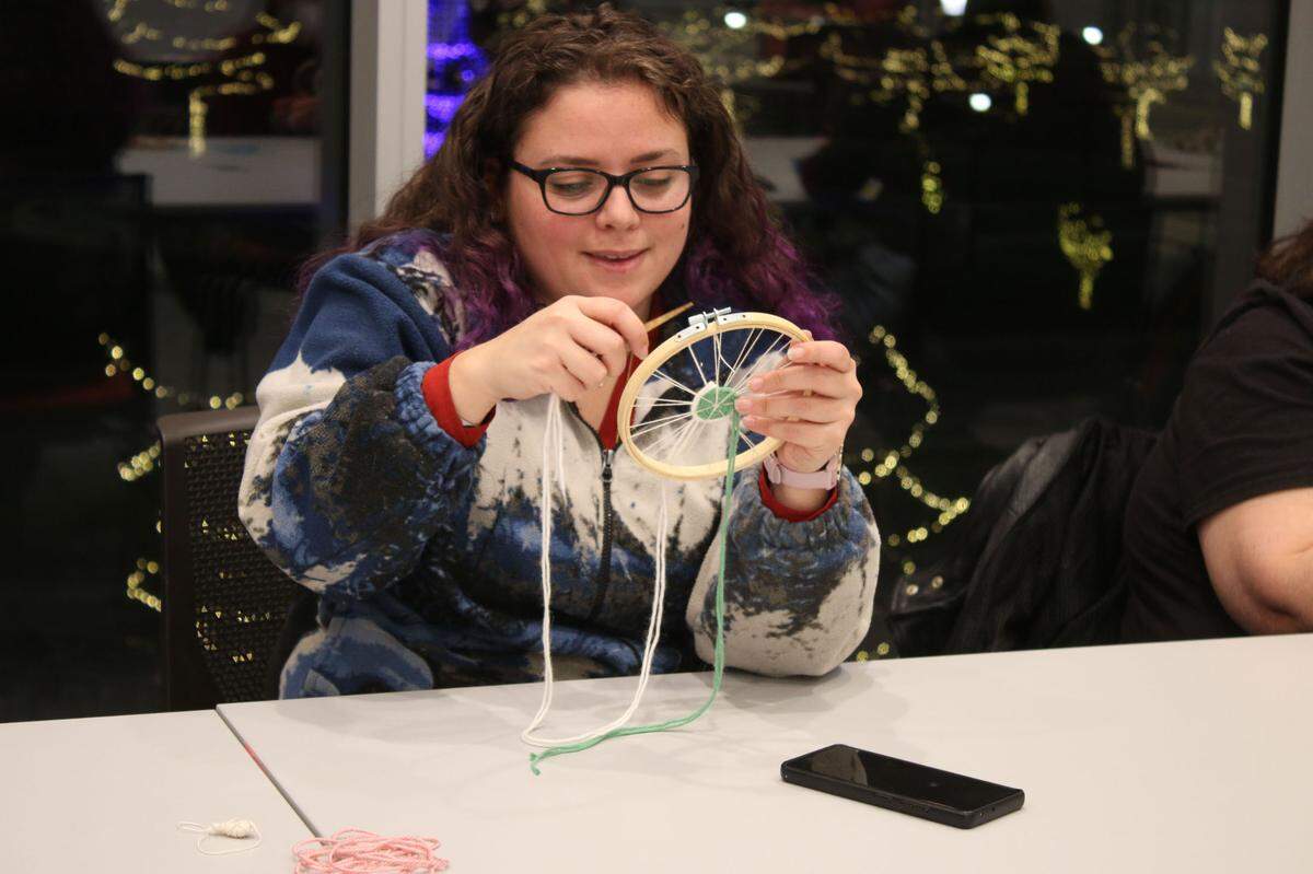 Amira Mogharbel of Overland Park adds a second color to her woven circle during a fiber arts class at the Downtown Olathe Library.
