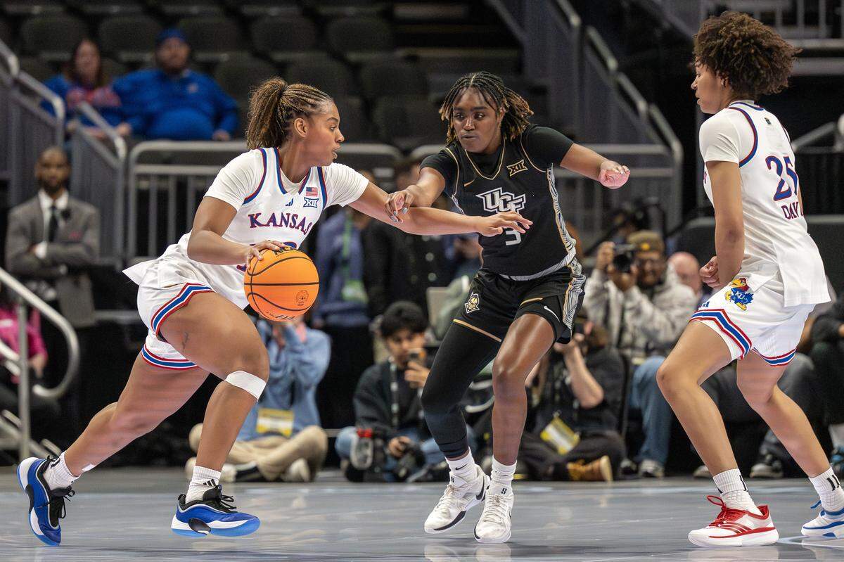 Kansas Jayhawks guard S'mya Nichols (No. 12, at left) dribbles while UCF Knights guard Jacorriah Bracey defends during a Big 12 Women's Basketball Tournament game at T-Mobile Center in Kansas City on Wednesday, March 4, 2026.