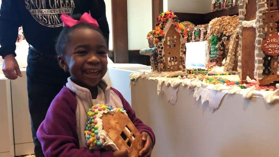 Khalecia Richards, 3, holds a gingerbread house at the National Museum of Toys and Miniatures in Kansas City on Monday. The Gingerbread Lane exhibit closed the previous day, and artist Jon Lovitch gave away many of the structures that made up the edible village.