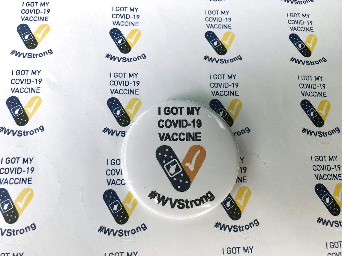 Stickers and a button given to people who receive their COVID-19 vaccines are displayed Thursday, Jan. 14, 2021, at the National Guard Armory in Charleston, W.Va. West Virginia has emerged an unlikely success in the nation’s otherwise chaotic vaccine rollout. (AP Photo/John Raby)