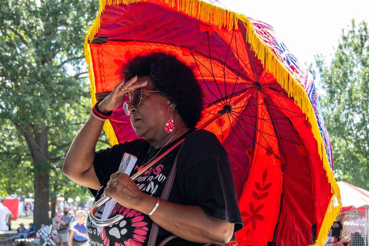 Khandi Meyers of Kansas City wipes sweat from her brow as she watches a dance performance at the Ethnic Enrichment Festival in Swope Park on Saturday, Aug. 16, 2025, in Kansas City. The annual festival celebrates the many different cultures and ethnicities that exist in Kansas City, with vendor booths, cultural education opportunities, and performances. Temperatures reached nearly 100 degrees.