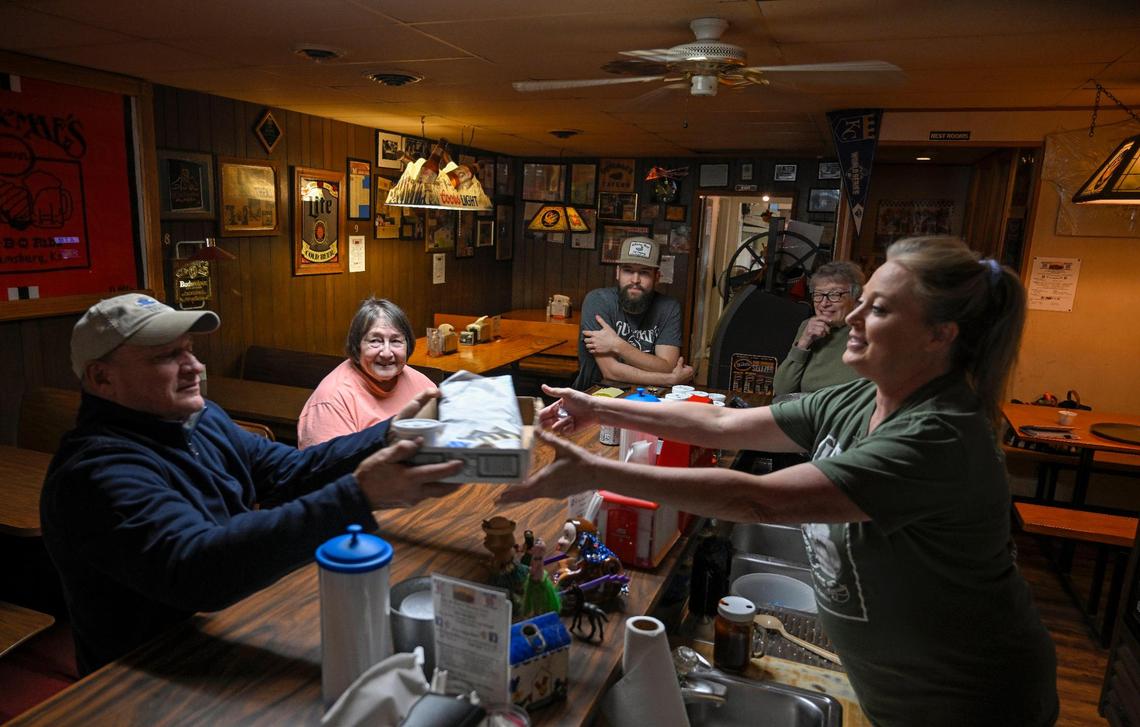 Customer Fred Defenbaugh, left, of Baldwin City, stops by to pick up a to-go order of hickory-smoked ribs from server Tammy Harabin, right, on a cold afternoon in November, while Wyatt Thompson and second-generation owners Judy Simpson and Diana Macoubrie look on. 