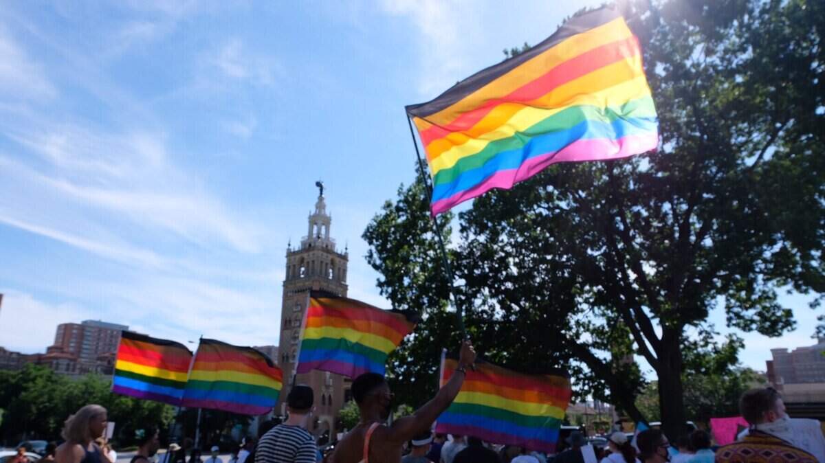 Several demonstrators carry Pride flags at a protest by the County Club Plaza on June 6, 2021.