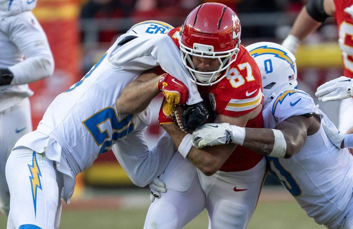 Kansas City Chiefs tight end Travis Kelce (87) runs for yardage against Los Angeles Chargers cornerback Cam Hart (20) and linebacker Daiyan Henley (0) in the second half on Sunday, Dec. 14, 2025 at GEHA Field at Arrowhead Stadium in Kansas City. The Chargers defeated the Chiefs, 16-13.