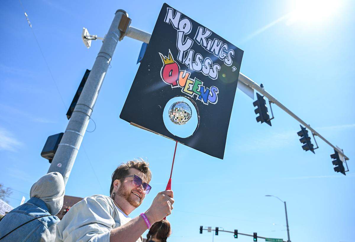 Aleka Soifua holds up a sign at a No Kings protest against the Trump administration in Mill Creek Park near the Country Club Plaza on Saturday, March 28, 2026, in Kansas City.
