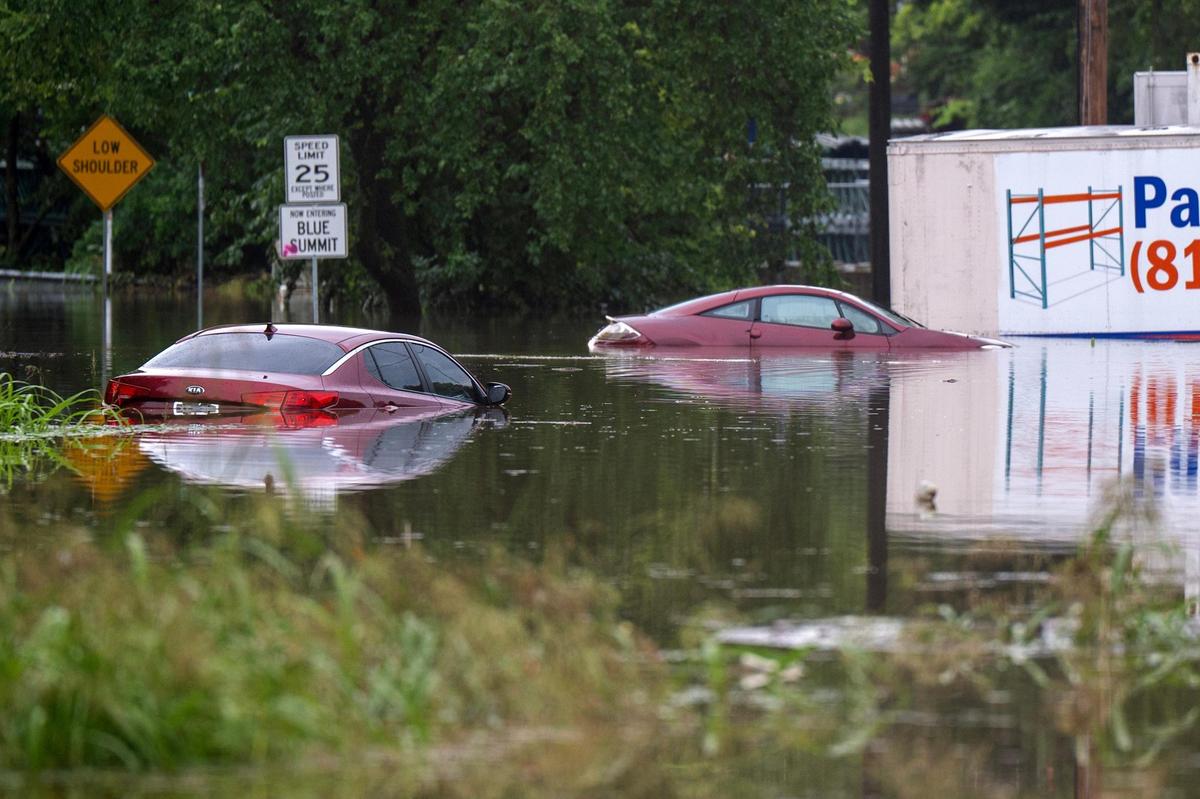 Two vehicles sit nearly fully submerged in floodwaters at Telephone Place and East 23rd Street on Thursday, July 17, 2025, in Kansas City. Heavy overnight rainfall caused flash flooding in parts of the city.