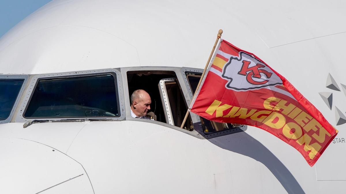 A pilot with United Airlines flies a Kansas City Chiefs flag out of a cockpit window as the team boards the plane for the 2023 Super Bowl at Kansas City International Airport. The Chiefs lend their name to a departure procedure at MCI.