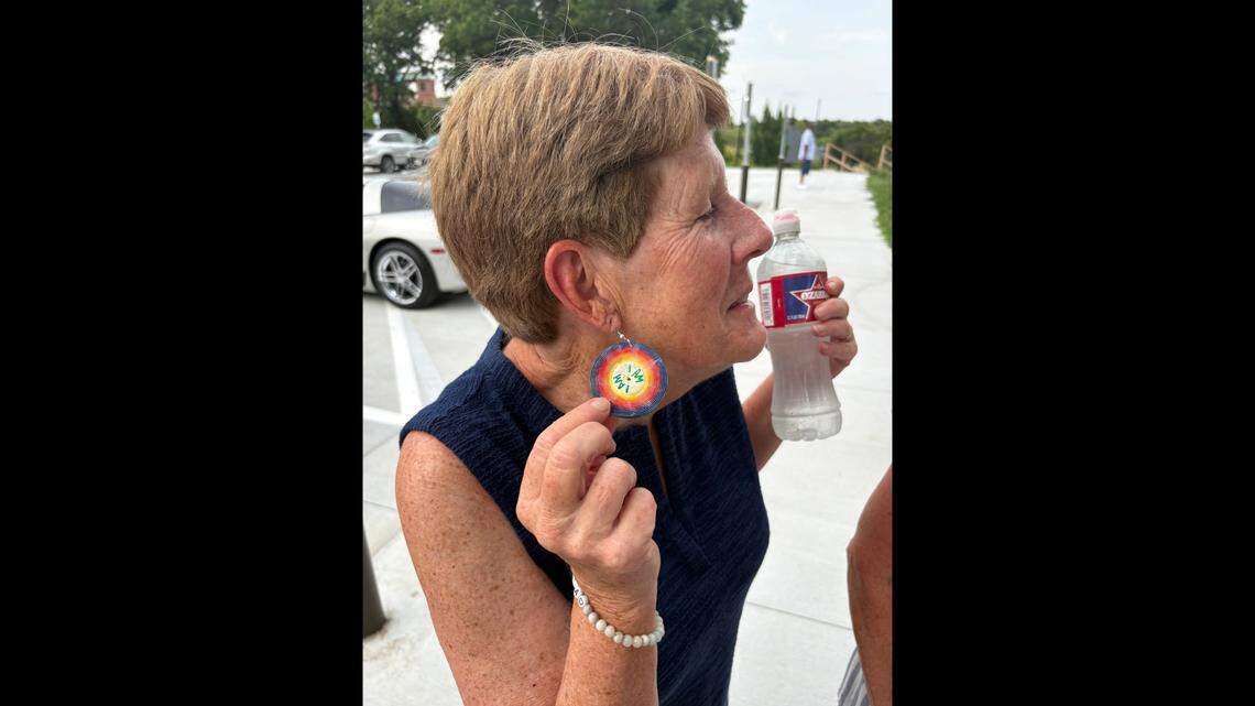 Iowa native Kathy Barsness flashes custom earrings dedicated to Earth, Wind, and Fire’s “I Am” album before attending the soul band’s show on Friday at Starlight Theater.