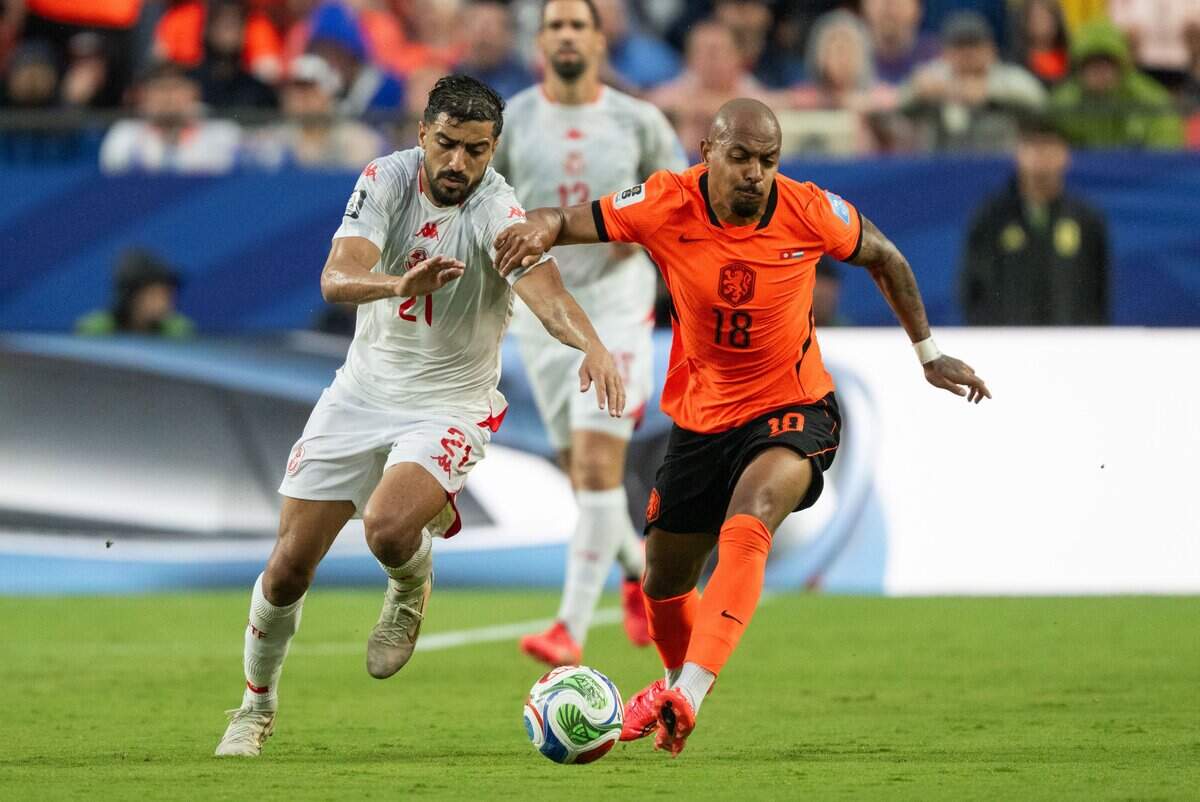 Netherlands midfielder Donyell Malen (18) fights for the ball against Tunisia defender Mohamed Amine Ben Hamida (21) in a FIFA World Cup group-stage soccer match at Kansas City (Arrowhead) Stadium in Kansas City on Thursday, June 25, 2026.