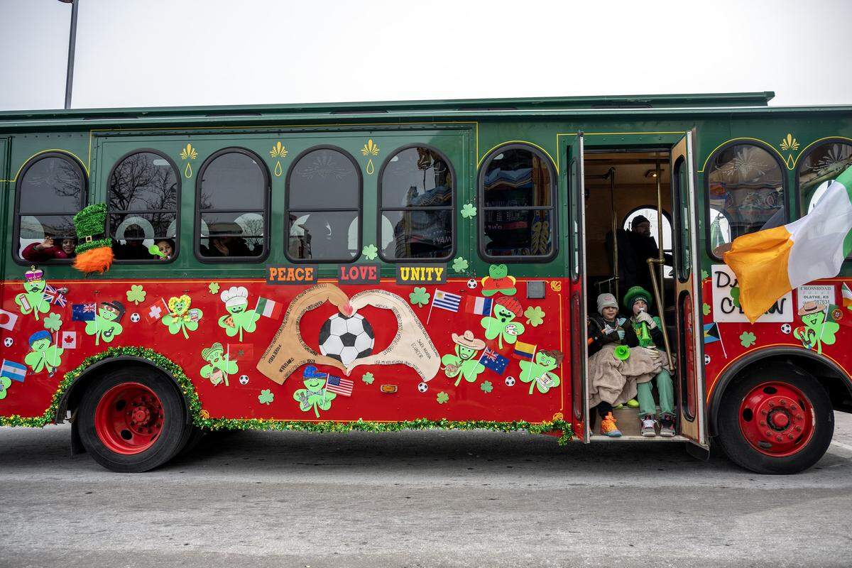 A trolley decorated with paper shamrocks and international flags cruises along Broadway Boulevard during the St. Patrick's Day parade on Tuesday, March 17, 2026, in Kansas City.
