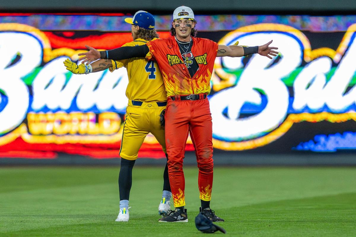 Savannah Bananas utility player KJ Jackson (4), left, and Firefighters outfielder Noah Bridges (9) perform a dance to “Breaking Free” from High School Musical during the eighth inning of a Banana Ball game at Kauffman Stadium on Friday, May 23, 2025, in Kansas City.