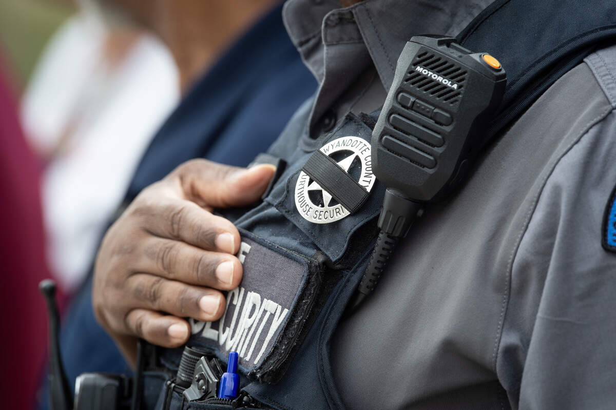A Wyandotte County courthouse security officer wears a blacked out badge while placing his hand on his heart while the funeral procession for Wyandotte County Sheriff's deputy Elijah Ming passes by on Monday, August 11, 2025, in downtown Kansas City, Kansas.