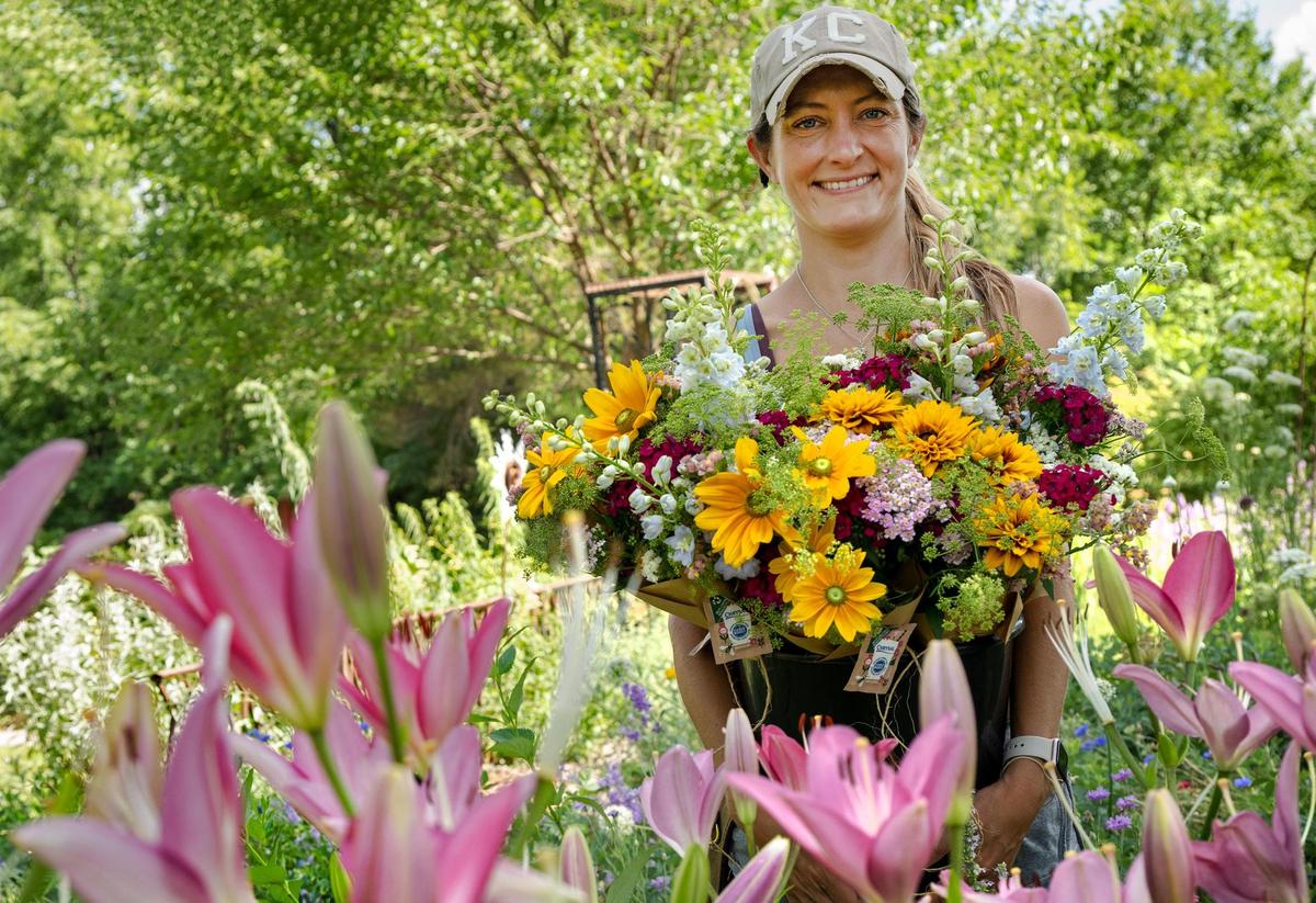 Ashley Hutchison, owner of Fern’s Farmette, juggles a heavy bucket filled bouquest of her speciality cut flowers in Eudora, Kansas. These flowers were used to make bouquets for her flower subscription customers who come to the farm to pick up the bouquets.