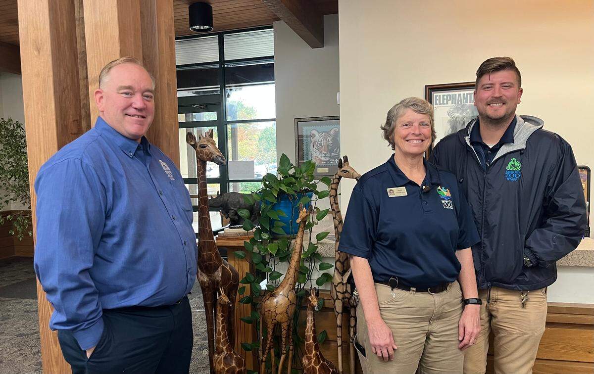 Sean Putney, the executive director at the Kansas City Zoo, Joni Hartman, the animal curator, and Jorge Rivera, a Kansas City Zoo team lead, smile for a picture in front of the giraffes on display in the administration office. Samantha Latson