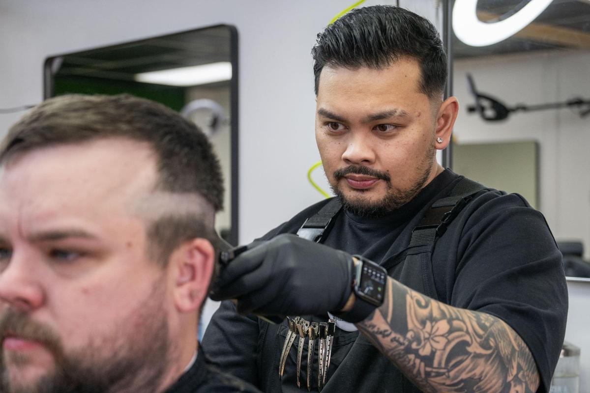 Josh Pacubas trims a client’s hair at his barbershop Dé Luxe Studios. Pacubas has overcome quite a bit in his life and now takes pride in being a positive voice for the people who come into his barbershop.