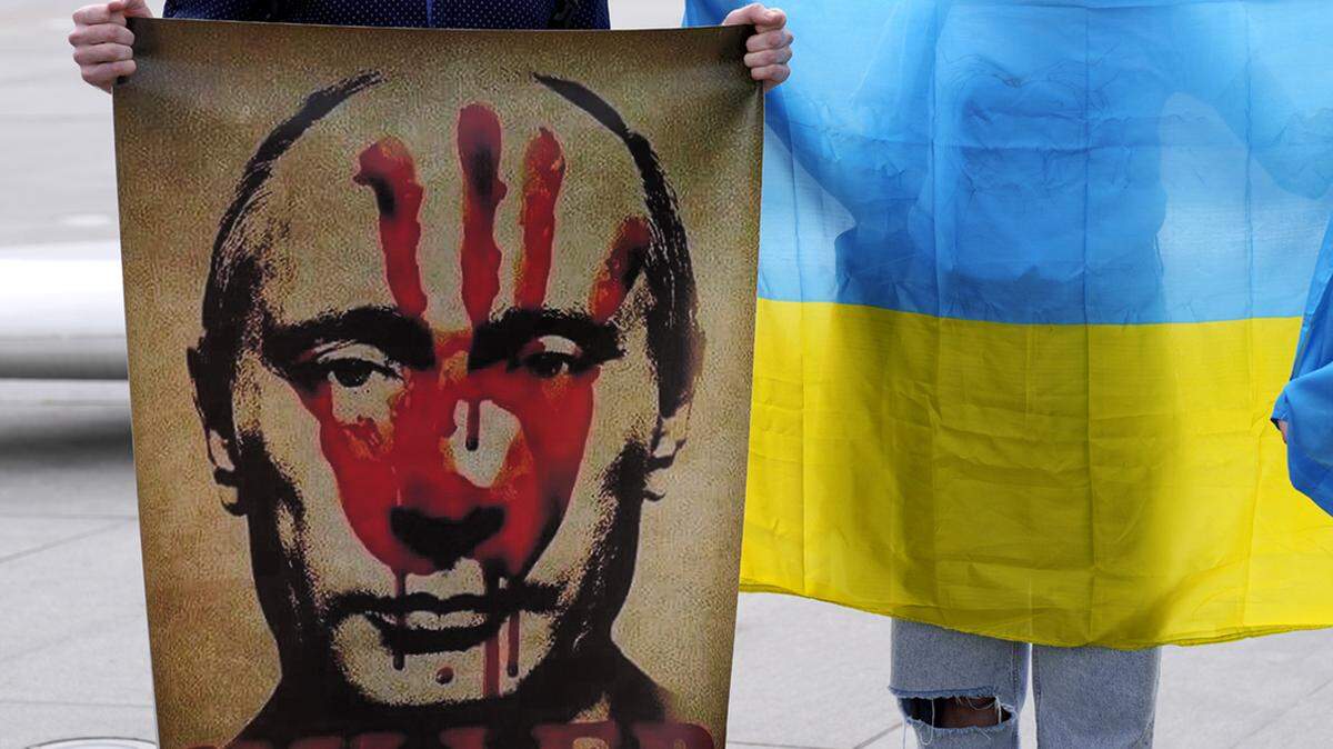 A protester holds a placard showing the Russian president Vladimir Putin as an other protester holds a Ukrainian flag during a protest against Russia’s invasion of Ukraine at Elephtheria, Liberty, square in central Nicosia, Cyprus, Saturday, March 5, 2022.