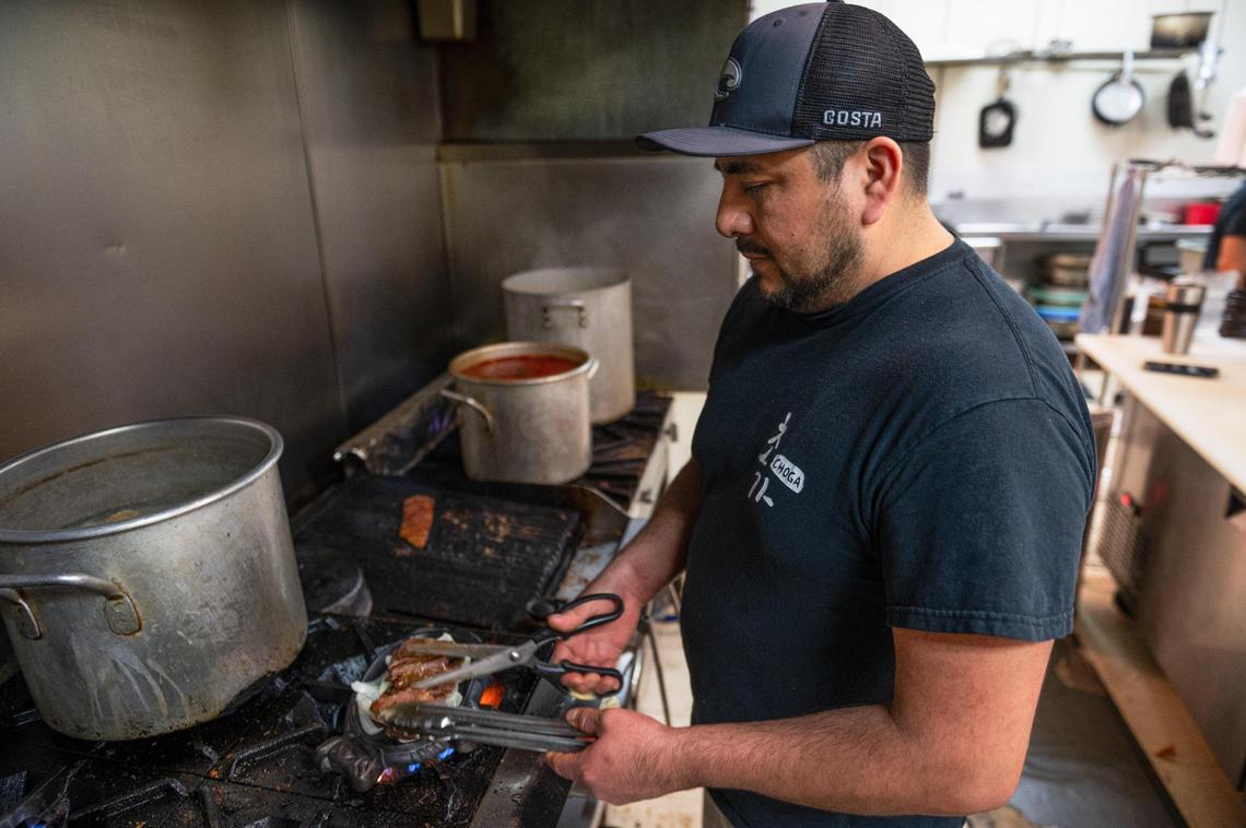 Aaron Ortiz cuts marinated short ribs onto a bed of yellow onions