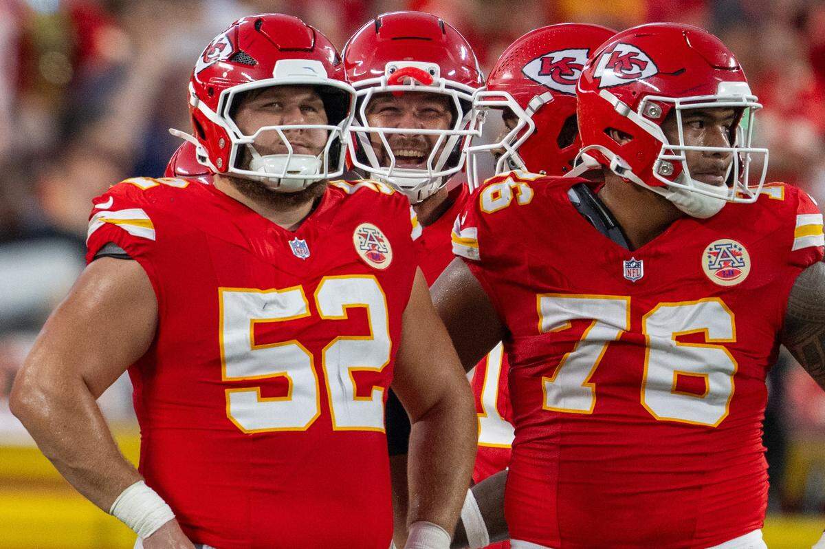 Kansas City Chiefs' Creed Humphrey (52) and Kansas City Chiefs' Kingsley Suamataia (76) wait for a play call while Kansas City Chiefs' Travis Kelce laughs in the background in the first quarter of the Chiefs preseason game vs. the Chicago Bears at GEHA Field at Arrowhead Stadium on Friday, Aug. 22, 2025, in Kansas City.