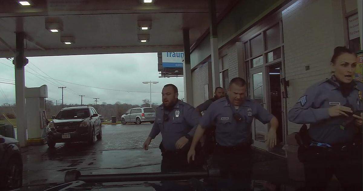 Kansas City police officer Jeremy Gragg, second from right, was shot in the leg on March 25, 2021. Dashboard camera footage shows him as he is about to get into a patrol vehicle to go to the hospital.