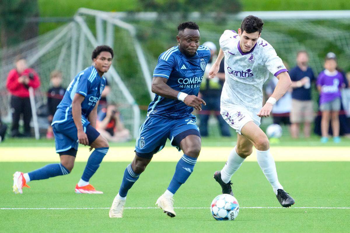 Sporting Kansas City forward Willy Agada, center, dribbles past Union Omaha midfielder Pedro Dolabella during Wednesday evening’s match at Caniglia Field in Omaha.