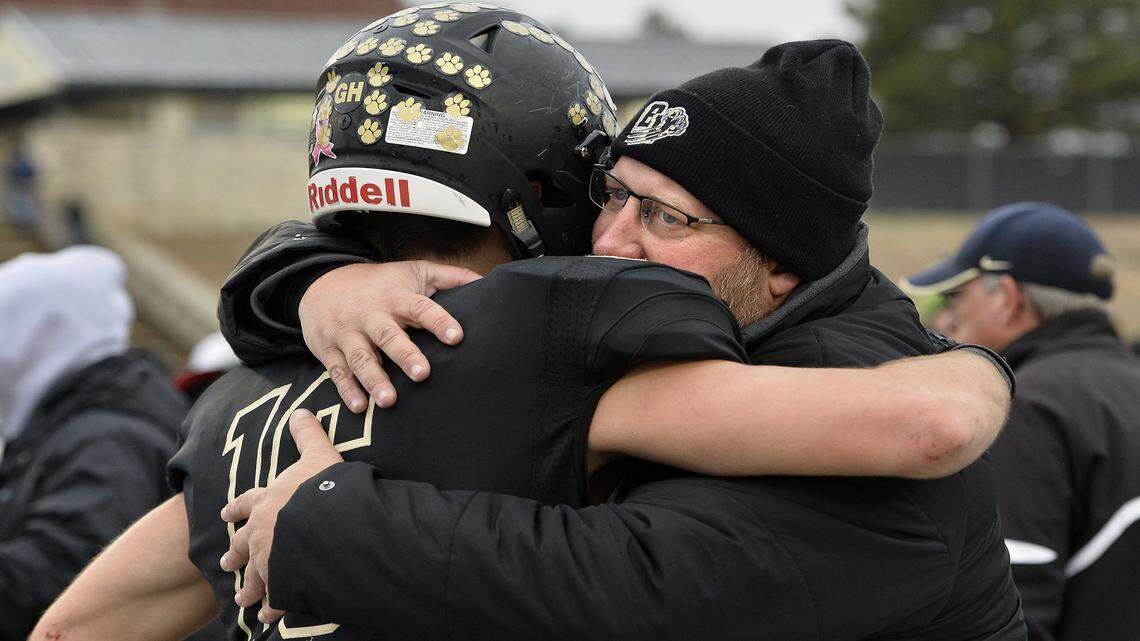 Blue Valley High School coach Eric Driskell, who died Wednesday, hugs senior Jacob Watson after Blue Valley lost to Derby 27-14 in the 6A state championship game in 2015. 