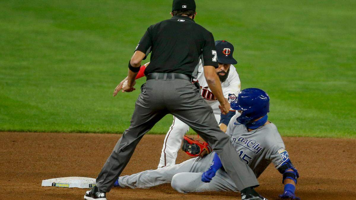 Minnesota Twins second baseman Marwin Gonzalez, center, tags out Kansas City Royals’ Whit Merrifield (15) who was trying to extend a single into a double as umpire Jose Navas, left, watches in the fifth inning of a baseball game Monday, Aug. 17, 2020, in Minneapolis. (AP Photo/Bruce Kluckhohn)
