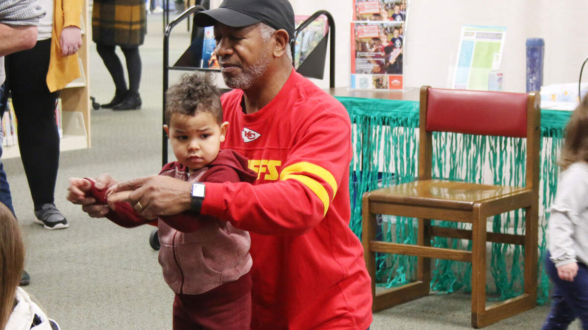 Lee’s Summit resident Anthony Lee helps his grandson, 3-year-old Brayden Lee, get the hang of the hukilau dance during the winter luau at the Colbern Road branch of the Mid-Continent Public Library.