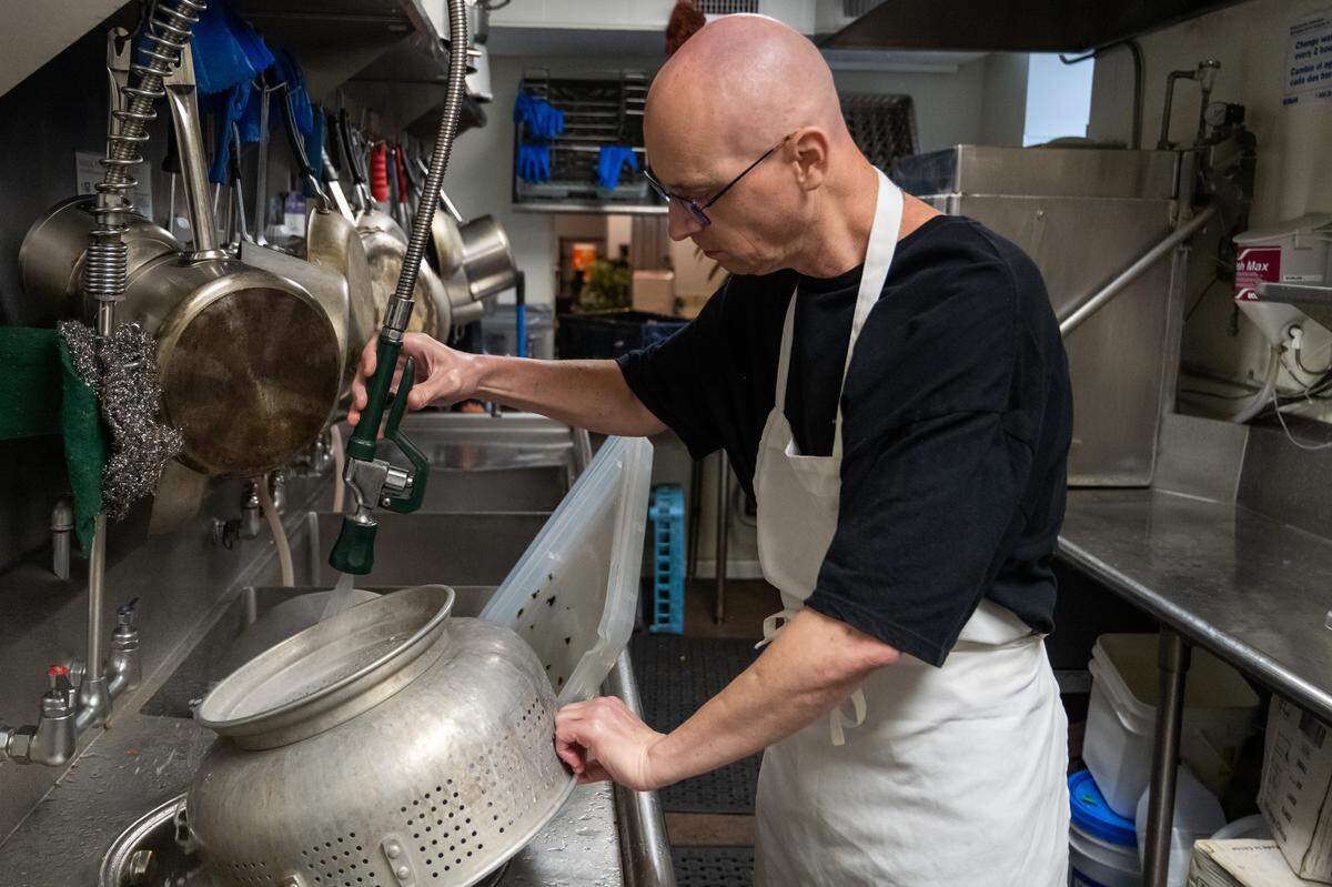 Phil Peterman volunteers to wash dishes prior to food service at Nourish KC, a community kitchen, on Thursday, November 6, 2025, in Kansas City. Homeless customers are able to come and eat a hot meal complete with service and a free pantry.