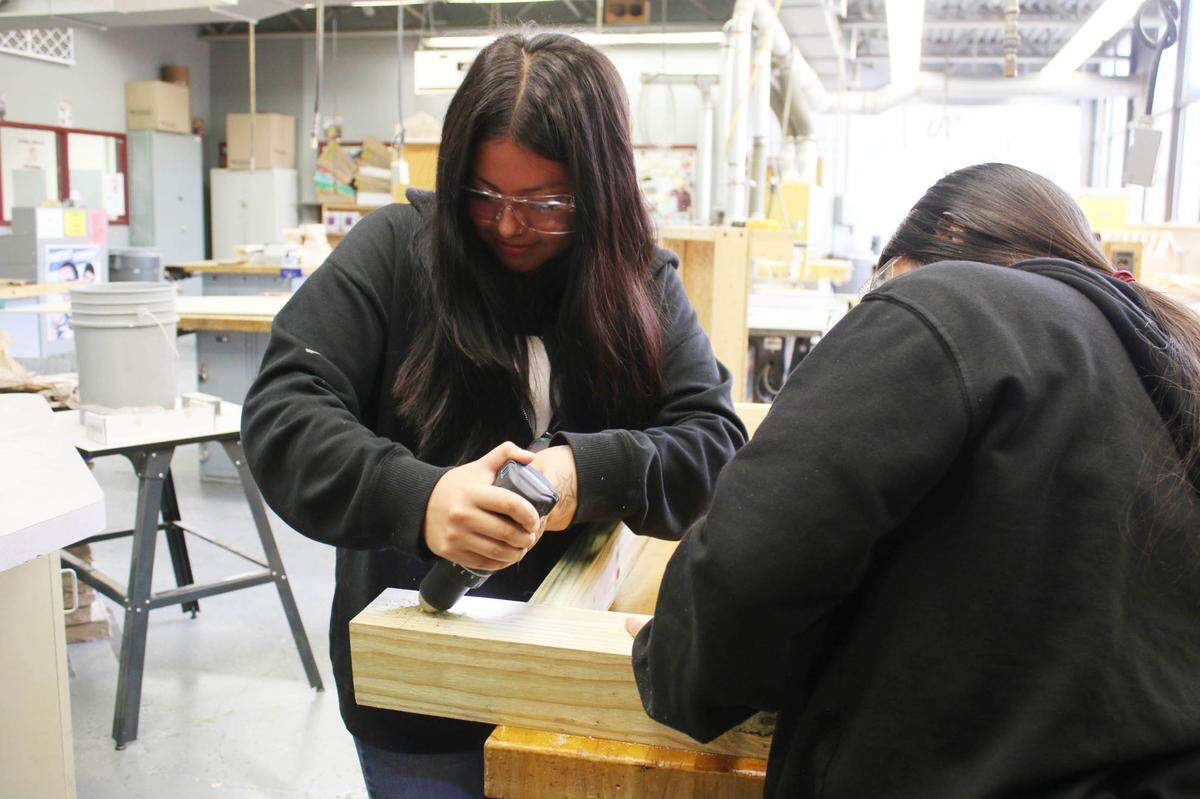 Olathe North sophomore Daysy Chavez drills a hole as classmate Xochilt Ibarra holds the piece of wood steady. Both are part of the Geometry in Construction class.