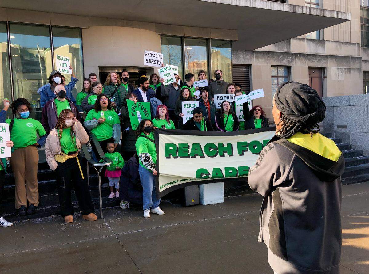 Members of Decarcerate KC held a rally outside Kansas City City Hall on March 2, 2024, advocating for a new REACH KC program that would provide alternate crisis response options in the community. The group held signs and chanted in between speakers who shared testimony about their experience during and after incarceration.