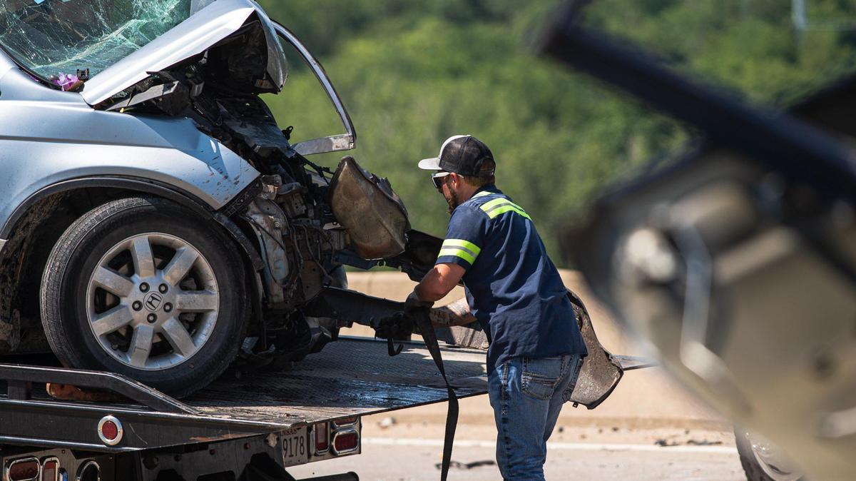 A member of a clean up crew prepares to tow a vehicle from the Seven Street Trafficway Bridge after a car wreck left one dead and two injured on Monday, June 19, 2023, in Kansas City, Kansas.