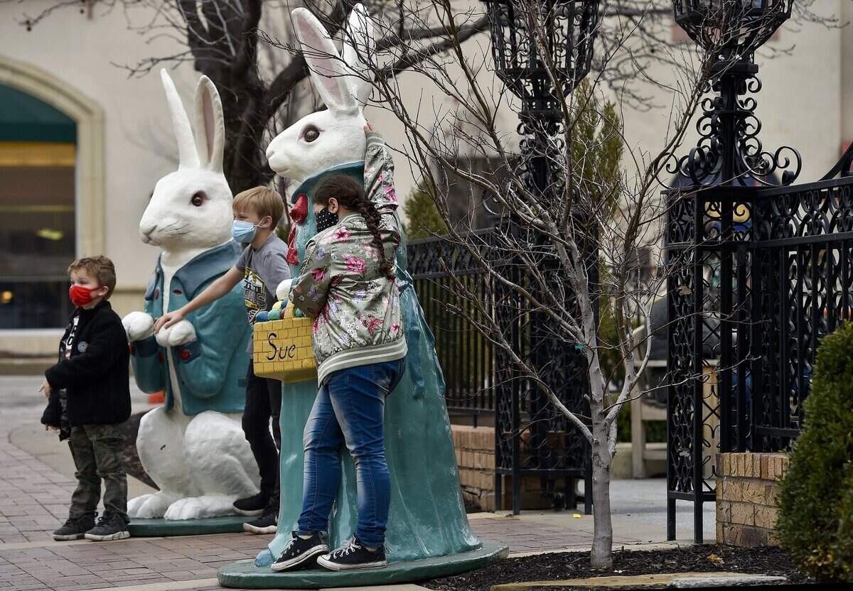 Six-year-old Kai Schnelle, from left, Michael Navarrette, 10, and Luci Stone, 8, pose with bunny statues named Peter and Sue, who stand near the Cheesecake Factory at Wyandotte Street and W. 47th Street.