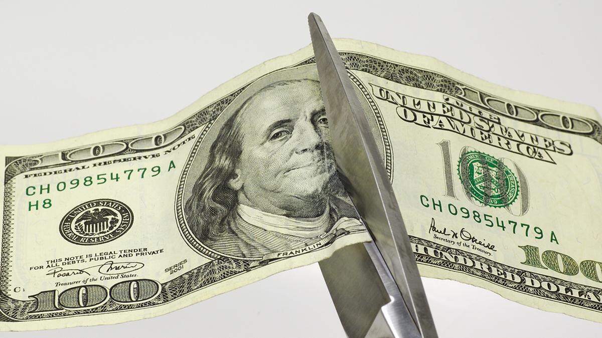 hundred dollar bill being cut with a scissor budget