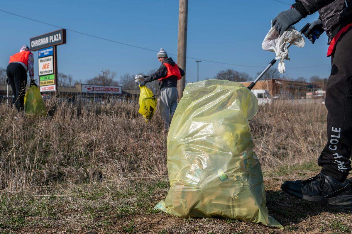 Members of Community Services League and Independence T.O.G.E.T.H.E.R. collect debris in yellow garbage bags along Independence Ave on March 30.