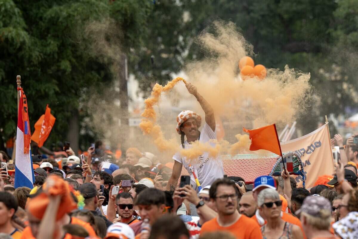 A pedicab operator releases orange smoke as fans celebrate during the Orange Walk on Thursday, June 25, 2026, in Kansas City.