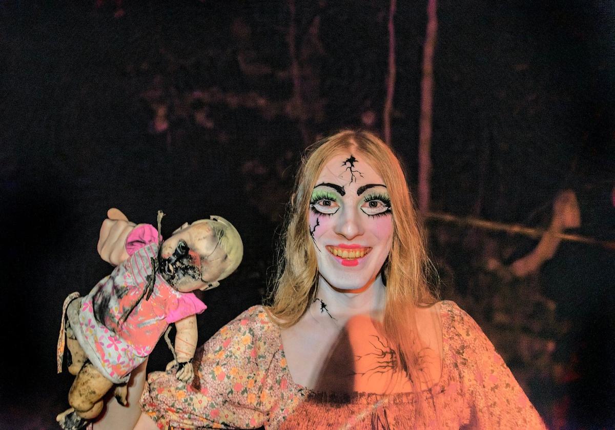 A scare actor shares her disfigured doll at Exiled KC-Crooked Rose Woods.