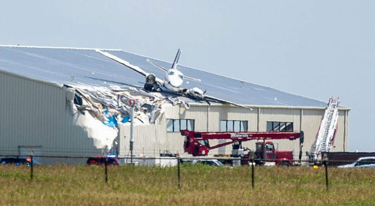 A Beechcraft airplane rests on the roof of a building at New Century AirCenter after it made a crash landing that left it on the roof on Monday, June 16, 2025.