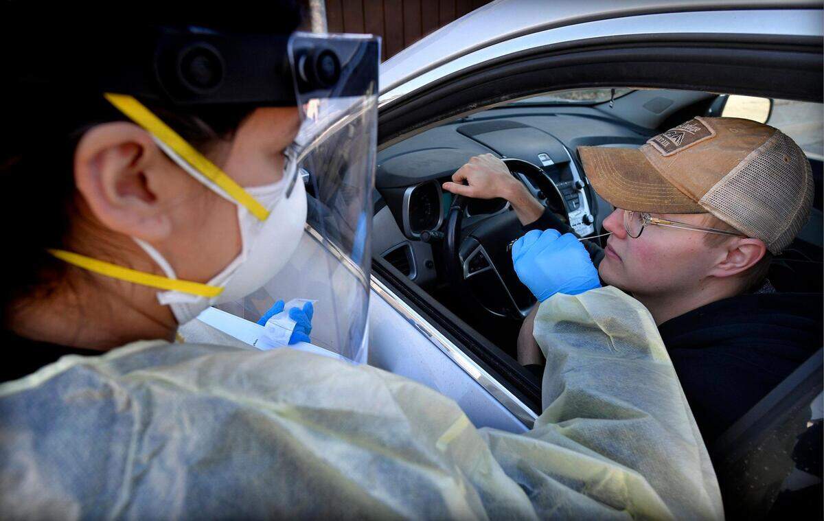 Breana Slusser, a medical assistant at Family Health Care KC performs a COVID-19 test for Grant Johnson of Kansas City on Tuesday, Dec. 21, 2021, at the clinic in Kansas City, Kan., Johnson, a medical student at The University of Kansas, needed a negative test to travel to Jamaica on Wednesday. In addition to the COVID-19 tests, the clinic is offering COVID-19 vaccinations and booster shots.