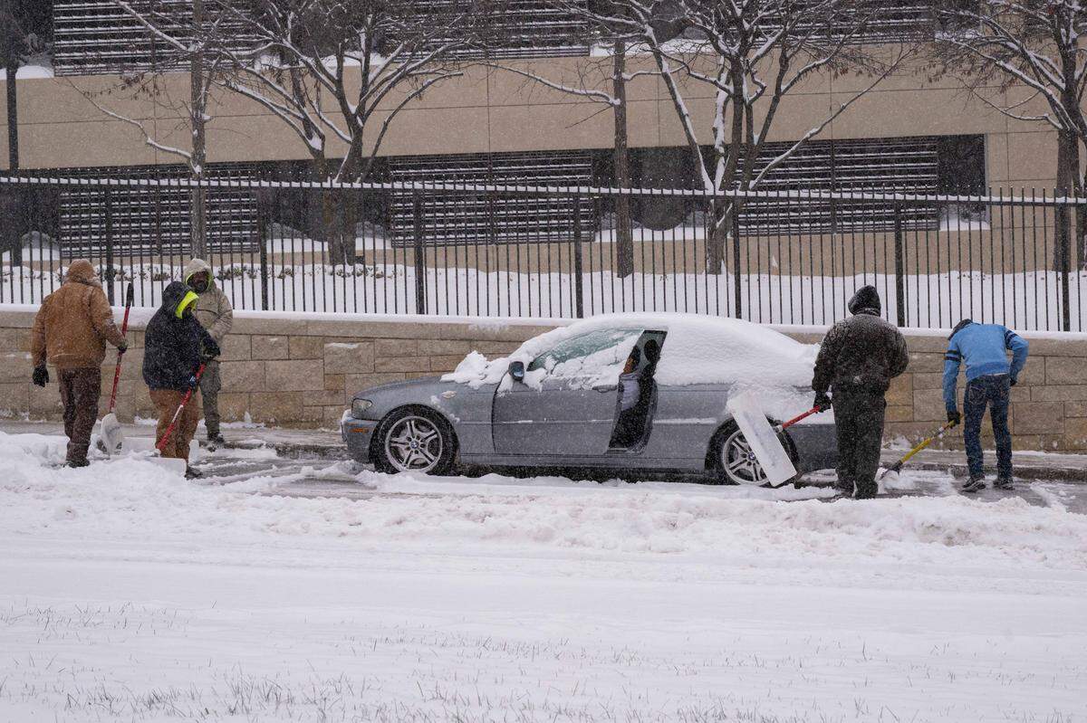 Good samaritans dig out a stuck vehicle along Main Street in Midtown as snow blanketed the Kansas City metro area on Monday.