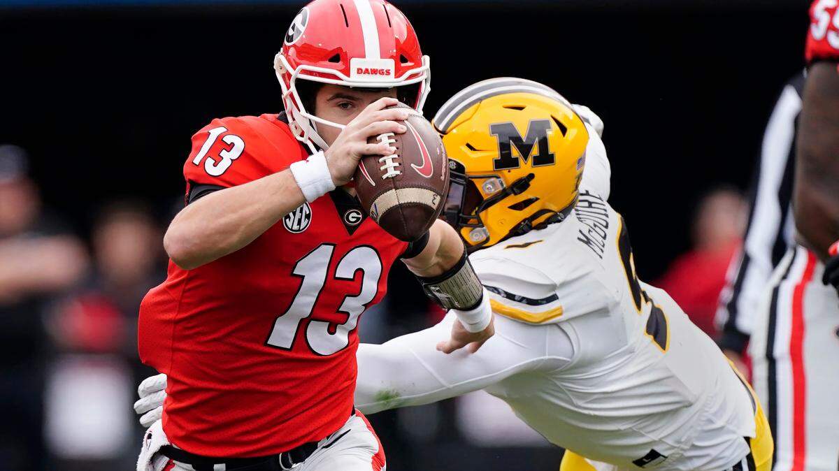 Georgia quarterback Stetson Bennett (13) gets past Missouri defensive lineman Isaiah McGuire (9) in the first half of an NCAA college football game Saturday, Nov. 6, 2021, in Athens, Ga.. (AP Photo/John Bazemore)