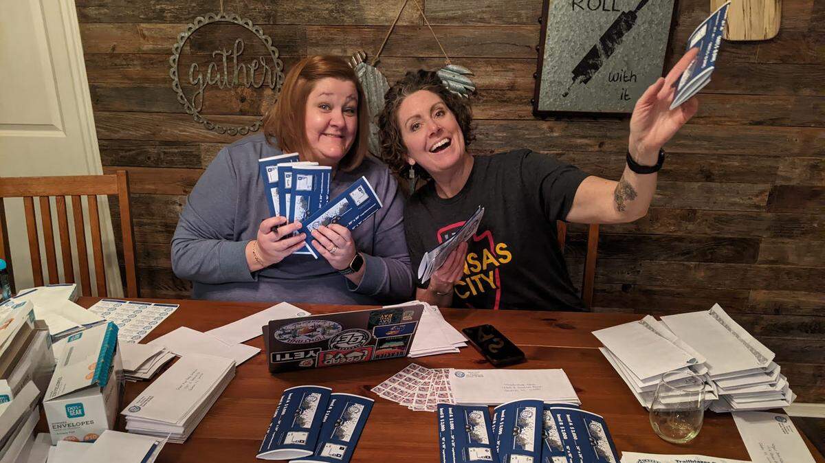 Stephanie Bryan and Amy Higgins stuff envelopes to mail to local businesses and nonprofit groups asking for sponsorship of the band trailer.