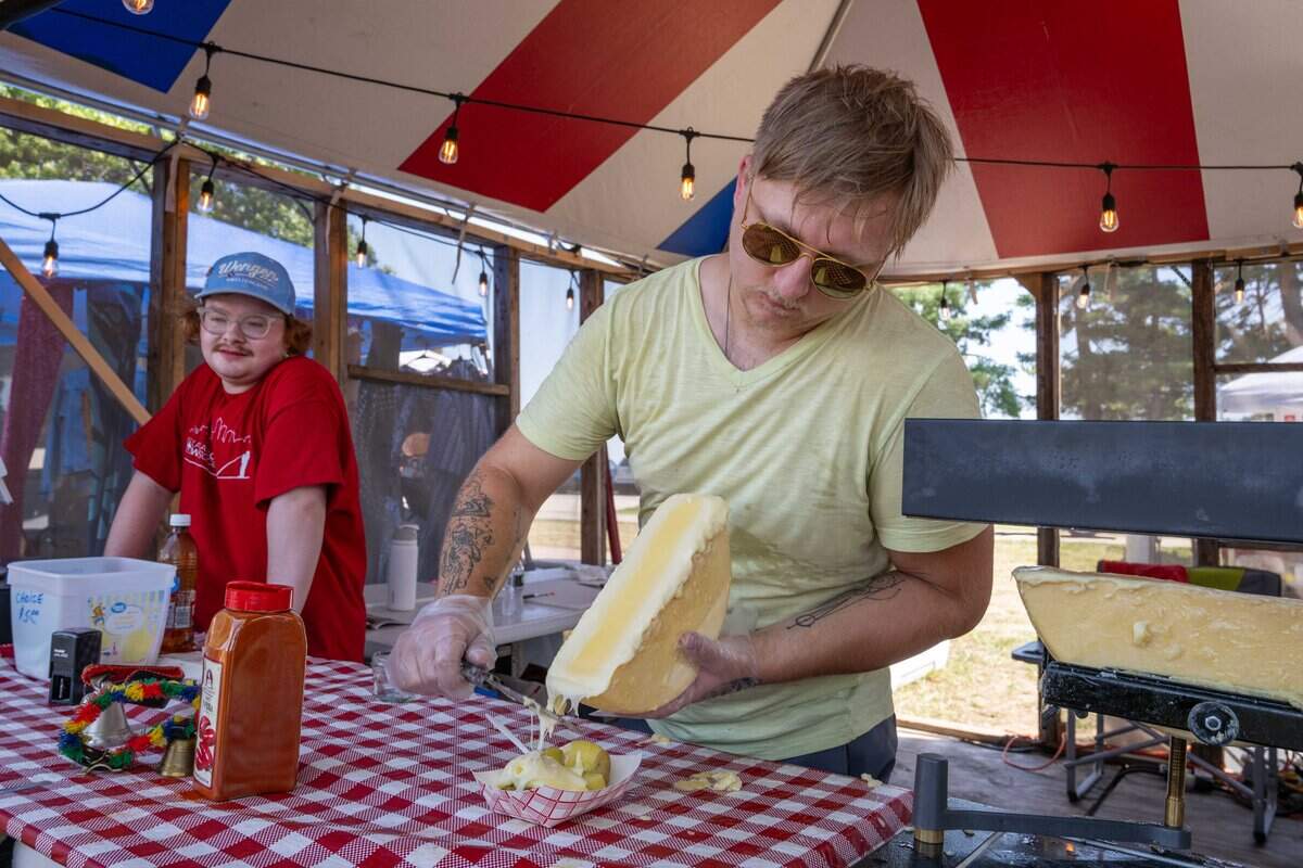 Jakob Knechtenhof pours melted cheese over potatoes inside the Switzerland food stand at the Ethnic Enrichment Festival in Swope Park on Saturday, Aug. 16, 2025, in Kansas City. The annual festival celebrates the many different cultures and ethnicities that exist in Kansas City, with vendor booths, cultural education opportunities, and performances.