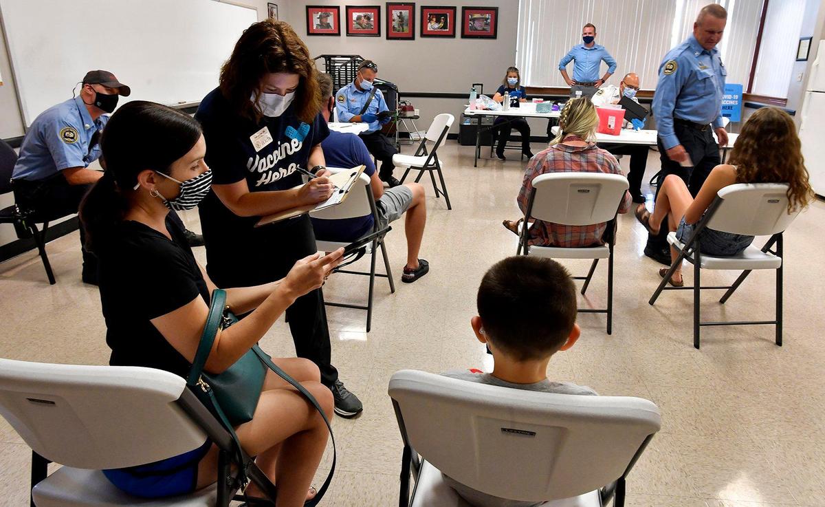 Toni Cowger, a community health nurse with the Springfield-Greene County Health Department, helps Amanda Wilson, left, of Springfield, fill out paperwork at a vaccination clinic Thursday at Fire Station No. 1. The day before, Cowger attended the funeral of a relative, 32, who had refused to get vaccinated and died of COVID-19.