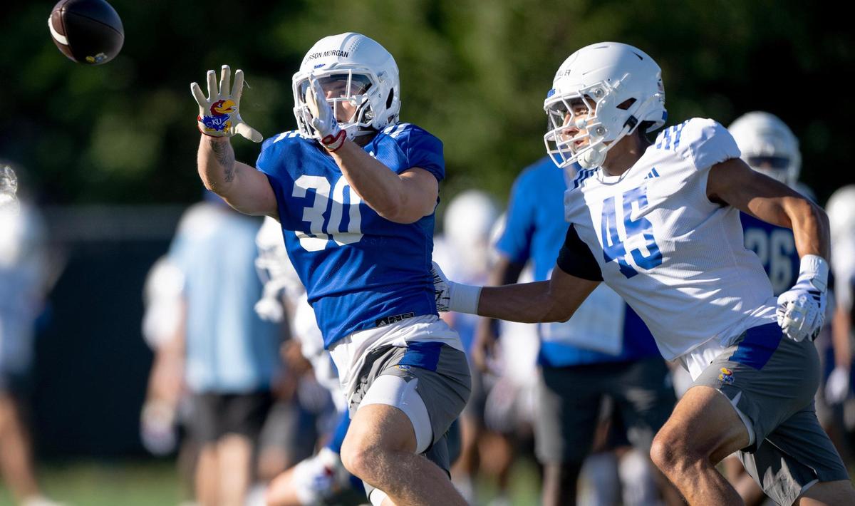 Kansas running back Carson Morgan (30) catches a pass as defensive end Dean Miller (45) defends during a KU football practice on Wednesday, Aug. 16, 2023, in Lawrence, Kan.
