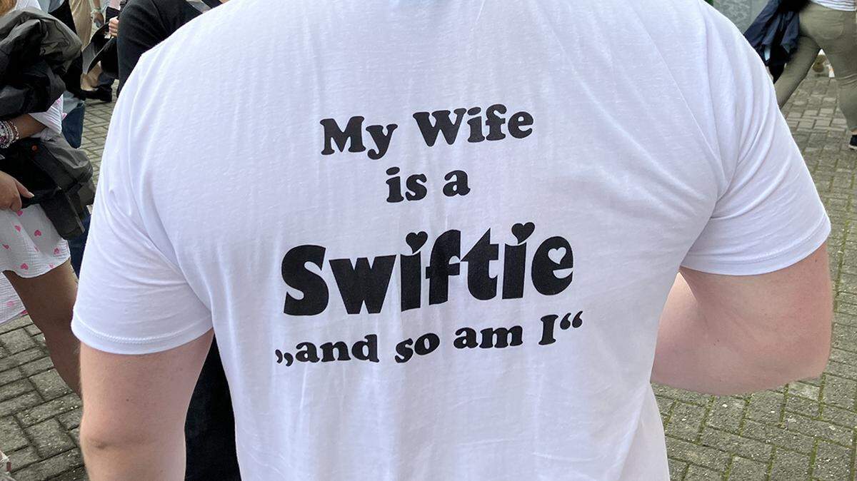 23 July 2024, Hamburg: A husband who goes to a Taylor Swift concert “just for the love of his wife” shows this with his T-shirt. Swift is giving a second concert in the Hanseatic city as part of her “The Eras Tour” on 24.07.2024. Photo: Thomas M√ºller/dpa/Sipa USA