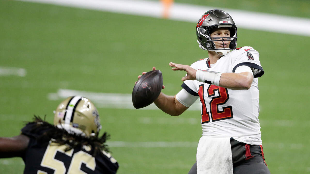 Tampa Bay Buccaneers quarterback Tom Brady (12) passes in front of New Orleans Saints outside linebacker Demario Davis (56) during the second half of an NFL divisional round playoff football game, Sunday, Jan. 17, 2021, in New Orleans. (AP Photo/Butch Dill)