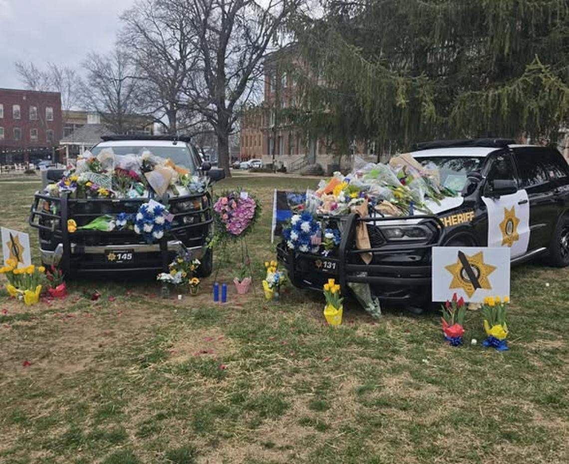 Flowers, wreaths and stuffed animals cover the patrol vehicles of Deputy Gabriel Ramirez, 30, and Deputy Michael Hislope, 40, outside the Christian County Courthouse in Ozark, Missouri. The two deputies were killed in the line of duty earlier this week.